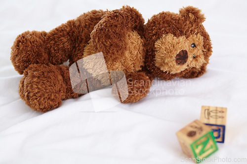 Image of Teddy bear, closeup and toys in bedroom with building blocks on a mattress for still life of development. Learning, letters and objects for childcare and play in home with plush animal and alphabet