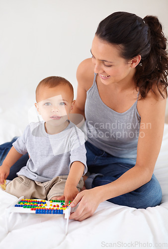 Image of Abacus, portrait and baby with mother playing, learning and education for child development on bed. Bonding, toy and young mom teaching kid, infant or toddler counting for math in bedroom at home