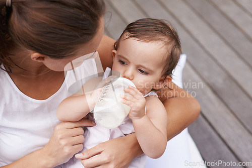 Image of Baby, mother and drinking formula for nutrition, food and relaxing together on porch at home. Mommy, toddler and bottle for health or child development in outdoors, feeding and milk for wellness