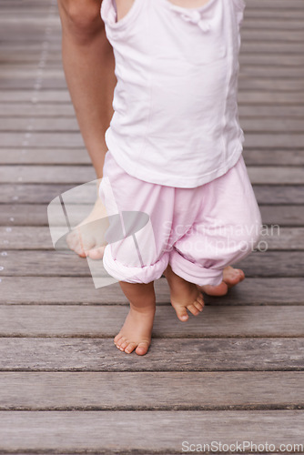 Image of Baby, feet and mom teaching with love, bonding and child care together and youth outdoor. Family, support and young kid with learning, holding and barefoot with trust, toddler and patio with mother