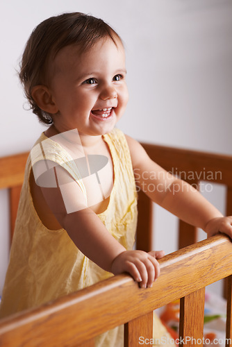 Image of Cute, laughing and a child in a crib for playing, wake up or comfort in a bedroom. Happy, baby and a young kid in a nursery or room for thinking, idea or innocent standing for development in a home