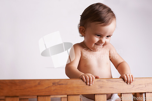 Image of Happy baby in crib, playing with smile and fun in home, child development and care in house. Toddler girl in cot with playful face, energy and curiosity in cute kids bedroom, nursery or apartment.