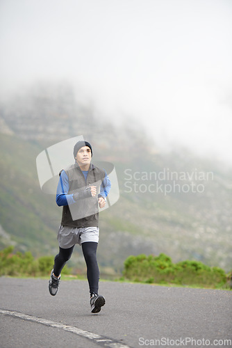 Image of Fitness, health and a man in the street for running, training and marathon competition. Winter, energy and a male runner or athlete in the road for sports, morning cardio or a workout in nature