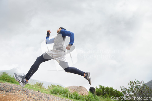 Image of Low angle, runner and man running in nature training, cardio exercise and endurance workout for wellness. Sports, fitness or healthy male athlete on fast jog on mountain outdoors with speed or action