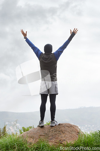 Image of Man, runner or victory on mountain peak for training adventure, exercise or workout success. Hill, fitness or back of hiker with hands up, gratitude or freedom in park to explore nature outdoors