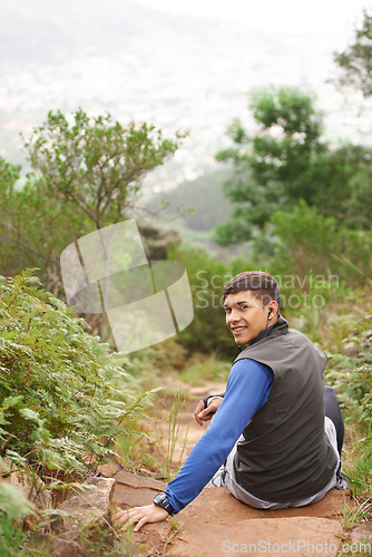 Image of Portrait, earphones or happy man on break in nature training, cardio exercise and workout for wellness. Radio music audio, fitness fatigue or back of tired athlete resting in forest or mountain trail