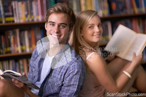 Image of Students, woman and man with books, portrait and smile for learning, scholarship or studying in college library. People, education and development with pride, knowledge or info on floor at university