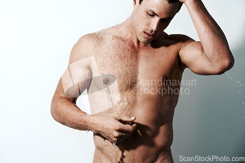 Image of Muscular man, water and shower for hygiene, grooming or washing body on a gray studio background. Young handsome male person or model cleaning skin with drops of liquid in bathroom on mockup space