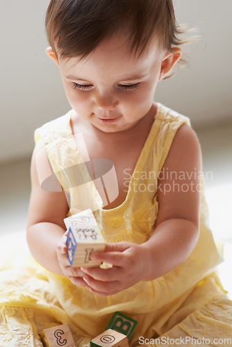 Image of Baby, playing and toys in living room floor, building blocks and sensory growth in family home. Curious, girl or play with child development for games, childhood or fun with smile, cognition or kids