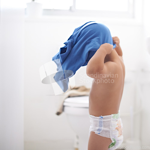 Image of Child, dressing and clothes in morning, home and learning to style or change into shirt in bathroom. Kindergarten, kid and development of independence in self care or changing into outfit for school