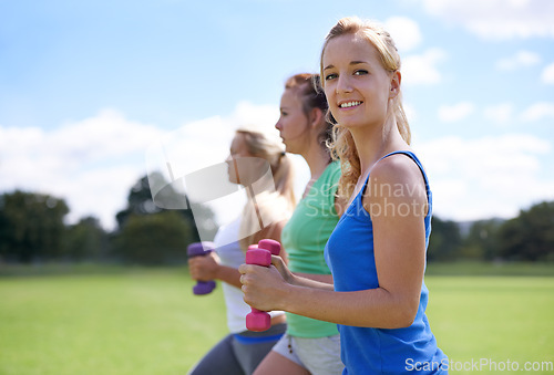 Image of Girl, group with dumbbells and weightlifting for fitness and muscle, strong athlete outdoor for sports on field. Portrait, exercise equipment in park and team workout together, endurance and strength