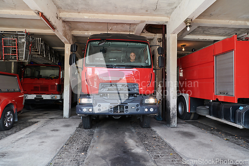 Image of A dedicated firefighter preparing a modern firetruck for deployment to hazardous fire-stricken areas, demonstrating readiness and commitment to emergency response