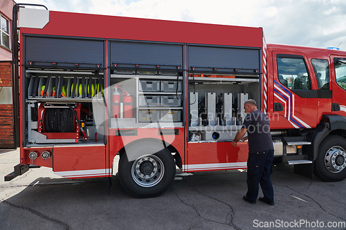 Image of A dedicated firefighter preparing a modern firetruck for deployment to hazardous fire-stricken areas, demonstrating readiness and commitment to emergency response