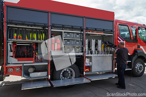 Image of A dedicated firefighter preparing a modern firetruck for deployment to hazardous fire-stricken areas, demonstrating readiness and commitment to emergency response