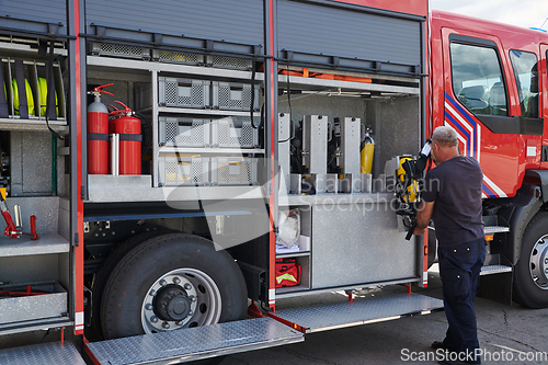 Image of A dedicated firefighter preparing a modern firetruck for deployment to hazardous fire-stricken areas, demonstrating readiness and commitment to emergency response