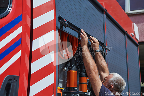 Image of A dedicated firefighter preparing a modern firetruck for deployment to hazardous fire-stricken areas, demonstrating readiness and commitment to emergency response