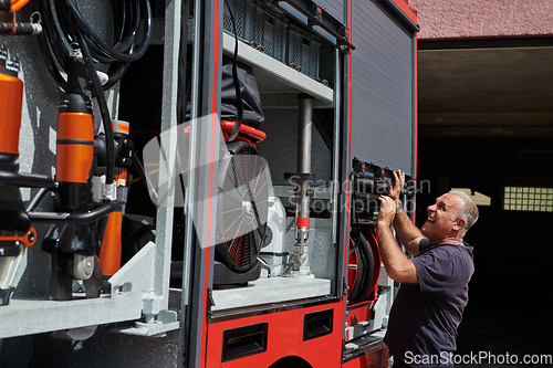 Image of A dedicated firefighter preparing a modern firetruck for deployment to hazardous fire-stricken areas, demonstrating readiness and commitment to emergency response