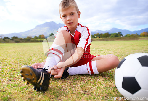 Image of Boy, soccer player and ball with shoe laces, portrait and ready for game, shoes or child. Outdoor, exercise and sport for childhood, person and athlete for match, training and workout on pitch