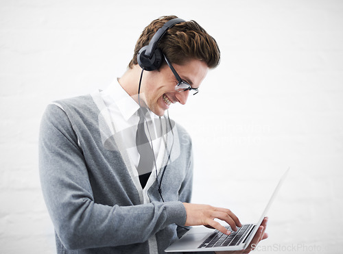 Image of Happy man, laptop and headphones listening to music, audio or streaming on a gray studio background. Male person, nerd or geek smile with computer and headset for sound or podcast on mockup space