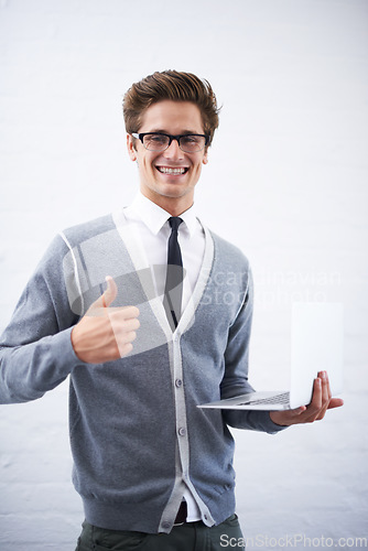 Image of Happy man, portrait and laptop with thumbs up for winning or good job on a gray studio background. Male person, nerd or geek smile with computer, like emoji or yes sign for approval on mockup space