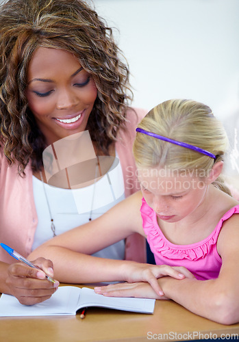 Image of Child, student with teacher and writing in classroom, learning and help for assessment or exam. Study, knowledge and education, woman and girl with notebook and pen for notes and info in class