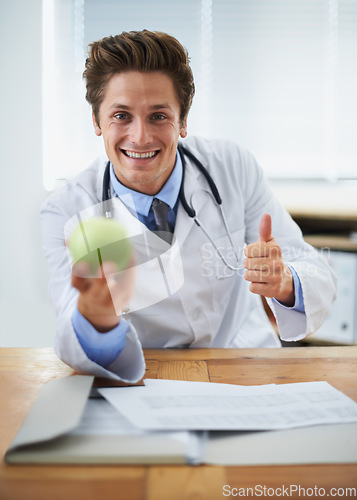 Image of Thumbs up, apple and portrait of man doctor with stethoscope for positive, good and confident attitude. Happy, smile and young healthcare worker with fruit in medical office of hospital or clinic.