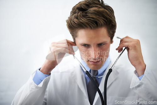 Image of Serious, stethoscope and young doctor with medical career in cardiology at medicare hospital. Doubt, thinking and professional male healthcare worker, employee or intern with equipment in clinic.