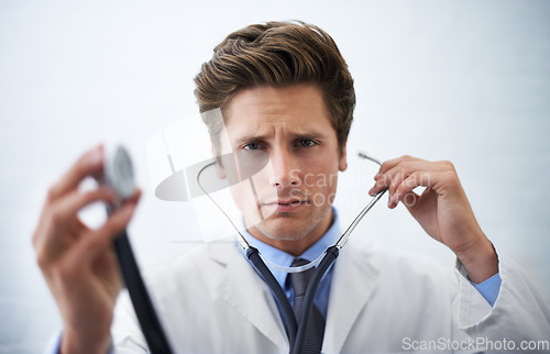 Image of Stethoscope, serious and portrait of doctor in office for medical consultation at hospital. Doubt, thinking and professional young male healthcare worker with equipment for career at medicare clinic