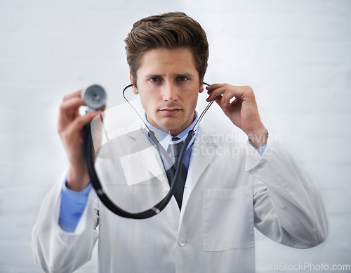 Image of Serious, portrait and man doctor with stethoscope in his office for medical consultation at hospital. Listen, career and professional young male healthcare worker or intern at medicare clinic.