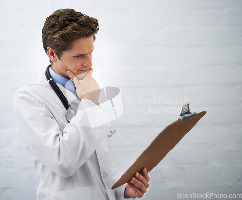 Image of Clipboard, thinking and man doctor in office for reading or brainstorming for diagnosis treatment. Ideas, checklist and professional young male healthcare worker with decision face at hospital