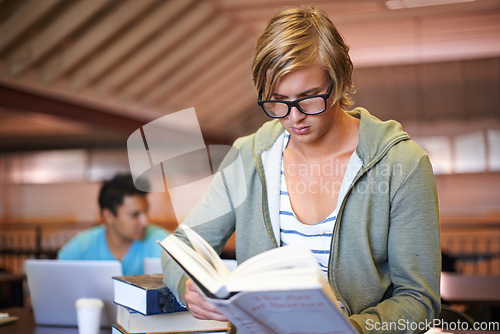 Image of Reading book, knowledge or student in library at university, college or school campus for education. Glasses, nerd or male person serious about scholarship studying, research or learning information
