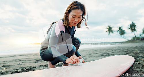 Image of Surfing, beach and woman waxing surfboard for water sports, fitness and freedom by ocean. Nature, travel and happy Japanese person on sand for wellness on holiday, vacation and adventure by sea