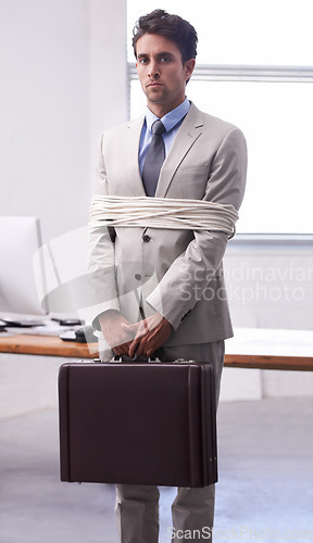 Image of Portrait of businessman in office tied up in rope with depression, control and fear in law firm. Serious attorney, lawyer or legal consultant bound at work, corporate hostage with bag and stress.