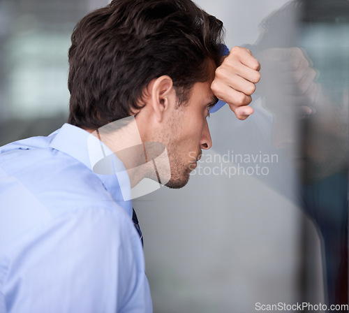 Image of Depression, business man and head on glass wall for financial crisis, reflection or anxiety for fail. Stress, frustrated and a tired professional in bankruptcy, debt and worry for office mistake