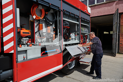 Image of A dedicated firefighter preparing a modern firetruck for deployment to hazardous fire-stricken areas, demonstrating readiness and commitment to emergency response
