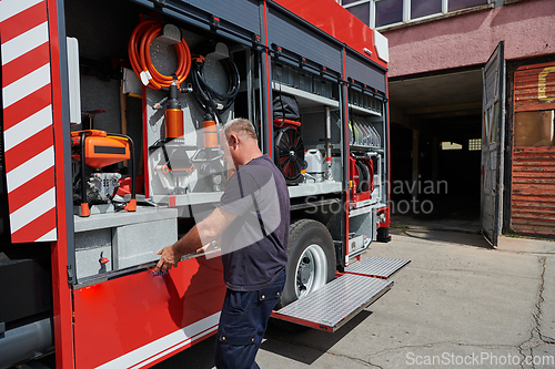 Image of A dedicated firefighter preparing a modern firetruck for deployment to hazardous fire-stricken areas, demonstrating readiness and commitment to emergency response