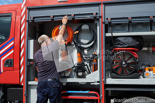 Image of A dedicated firefighter preparing a modern firetruck for deployment to hazardous fire-stricken areas, demonstrating readiness and commitment to emergency response