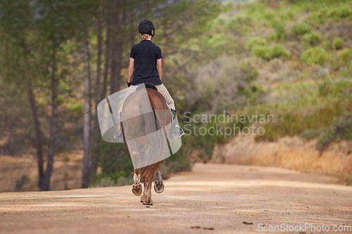 Image of Equestrian, trail and riding a horse in nature on adventure and journey in countryside. Ranch, animal and back of rider outdoor with pet on path in forest or woods for hobby on farm in summer