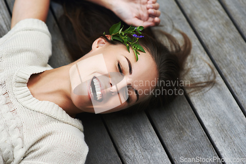 Image of Woman, face and happy on porch for relax outdoor in backyard with flower, lying down and rest in home. Person, spring and smile on wooden deck in garden of house or apartment with carefree or casual