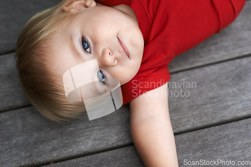 Image of Baby, playing on floor outdoor for development with portrait, curiosity or early childhood in backyard of home. Toddler, child and relax on ground for wellness, milestone and exploring or aerial view