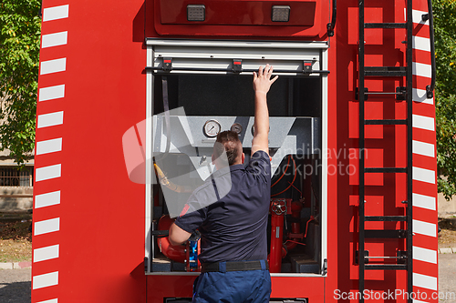 Image of A dedicated firefighter preparing a modern firetruck for deployment to hazardous fire-stricken areas, demonstrating readiness and commitment to emergency response