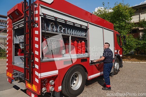 Image of A dedicated firefighter preparing a modern firetruck for deployment to hazardous fire-stricken areas, demonstrating readiness and commitment to emergency response