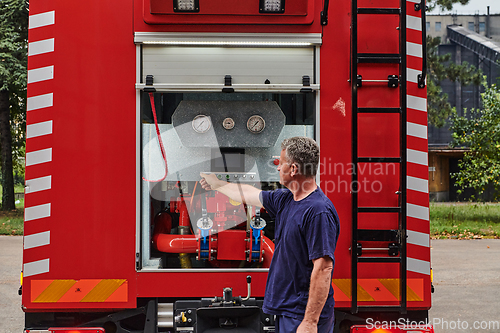 Image of A dedicated firefighter preparing a modern firetruck for deployment to hazardous fire-stricken areas, demonstrating readiness and commitment to emergency response