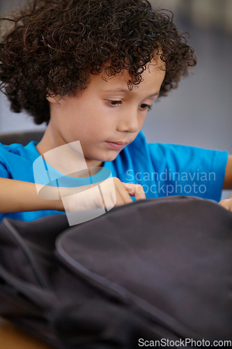 Image of Boy, education and school bag in a classroom, student and searching with learning, study and table. Kid, child development and happy with a backpack, desk and confident with information and relax