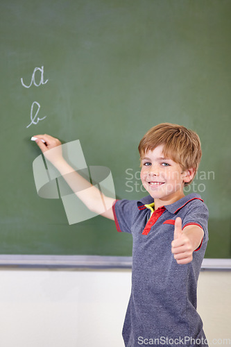 Image of Portrait, child writing or thumbs up on chalkboard in classroom of elementary school. Boy, education student or happy kid with smile or hand gesture for like emoji, agreement or learning to write