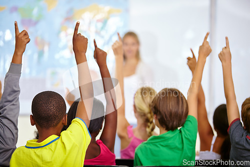 Image of Back of students, classroom and raise hands for questions, education or learning with geography quiz in school. Youth, group or smart kids with teaching for support, class ideas and answer or advice