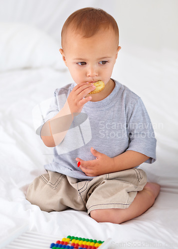 Image of Cute, bed and baby eating biscuit for yummy snack playing with abacus for education. Child development, sweet and hungry young boy kid, infant or toddler enjoying a cracker in bedroom at home.