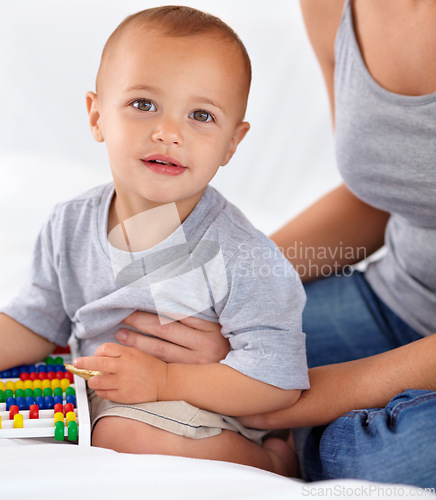 Image of Abacus, smile and portrait of baby with mother playing, learning and teaching for child development on bed. Bonding, toy and mom with kid, infant or toddler with counting in bedroom at home.