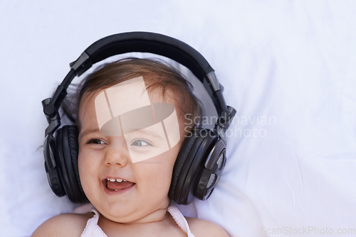 Image of Baby, headphones and listening to song for fun, above and face on bed at home. Child, happiness and hearing audio for child development or learning, toddler and calming playlist for peace and calm