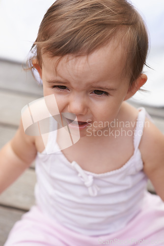 Image of Sad baby, face and sitting outside of curious toddler, little girl or disappointed on outdoor porch. Closeup of young unhappy child, upset kid or adorable cute newborn with frowning facial expression